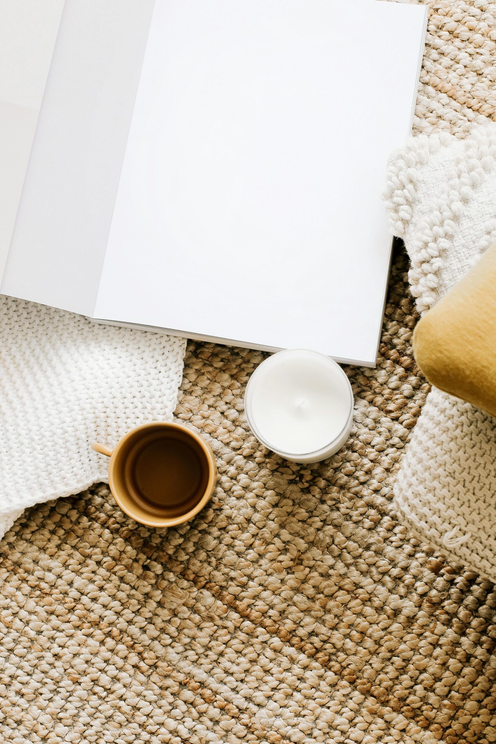 Top view arrangement of opened notebook with empty sheets placed on table near mug and candle